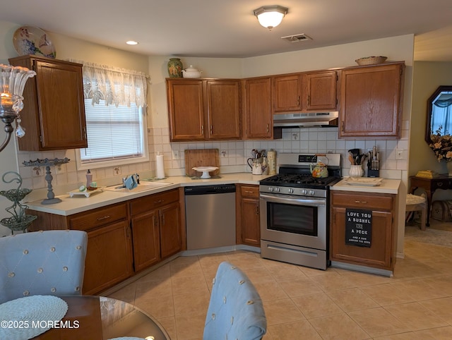 kitchen featuring light countertops, appliances with stainless steel finishes, visible vents, and under cabinet range hood