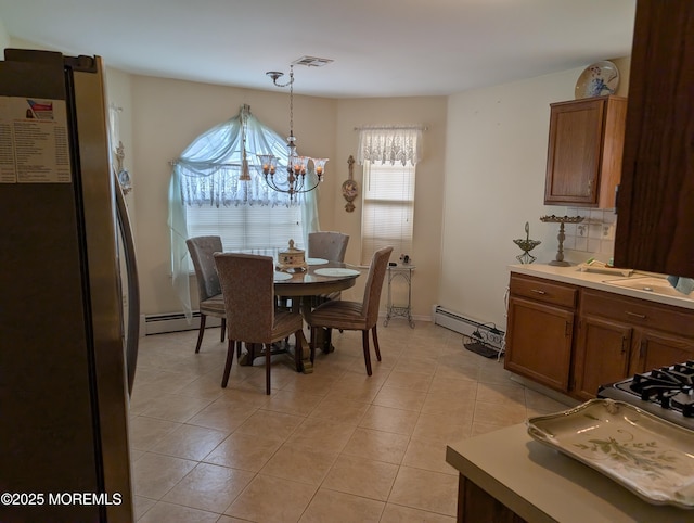 dining area with an inviting chandelier, light tile patterned floors, visible vents, and baseboard heating