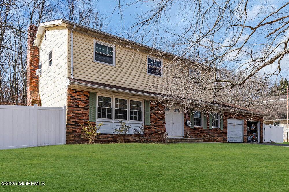 view of front facade with a garage, brick siding, a front lawn, and fence