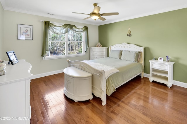 bedroom featuring hardwood / wood-style flooring, baseboards, visible vents, and crown molding