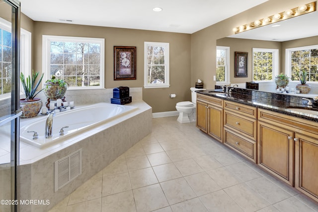 full bath featuring a garden tub, double vanity, visible vents, a sink, and tile patterned flooring