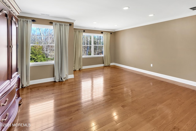 spare room with a wealth of natural light, baseboards, ornamental molding, and hardwood / wood-style floors