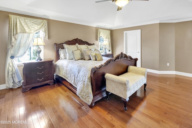 bedroom with ornamental molding, baseboards, hardwood / wood-style floors, and a ceiling fan