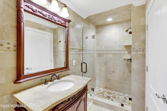 bathroom featuring crown molding, a shower stall, vanity, and tile walls