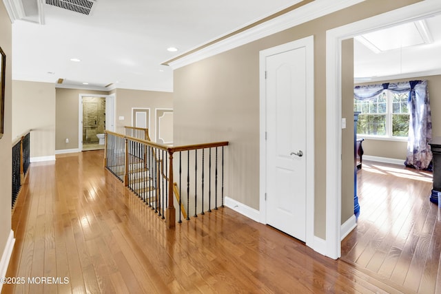 hallway with crown molding, visible vents, attic access, an upstairs landing, and hardwood / wood-style flooring