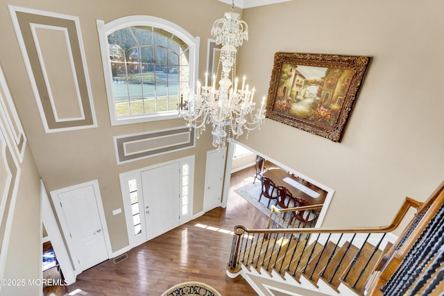 foyer with visible vents, stairway, a high ceiling, an inviting chandelier, and wood finished floors