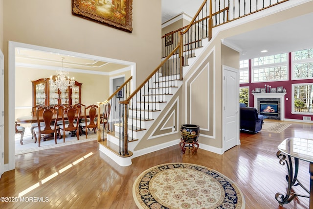 stairway with ornamental molding, hardwood / wood-style floors, a chandelier, and a towering ceiling