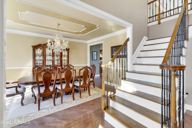 dining room featuring a notable chandelier, wood finished floors, baseboards, stairs, and crown molding