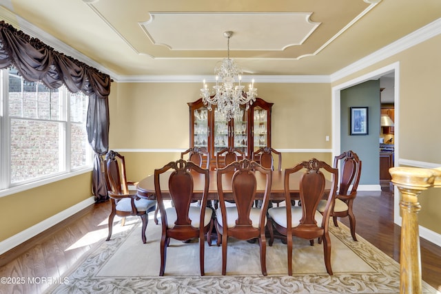 dining area featuring ornamental molding, a notable chandelier, baseboards, and wood finished floors