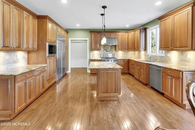 kitchen with built in appliances, brown cabinetry, light wood-type flooring, and under cabinet range hood