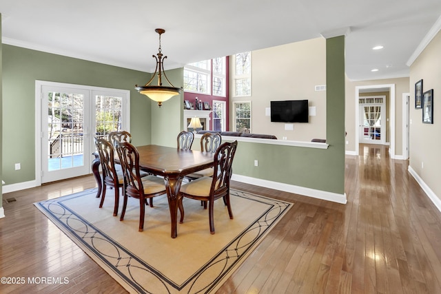 dining space with baseboards, hardwood / wood-style flooring, crown molding, a fireplace, and recessed lighting