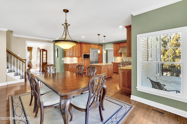 dining room with crown molding, recessed lighting, visible vents, light wood-type flooring, and baseboards