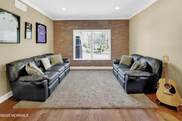 living area featuring ornamental molding, brick wall, and wood finished floors