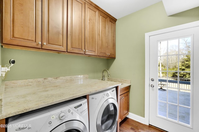 clothes washing area featuring a sink, wood finished floors, baseboards, cabinet space, and washing machine and clothes dryer