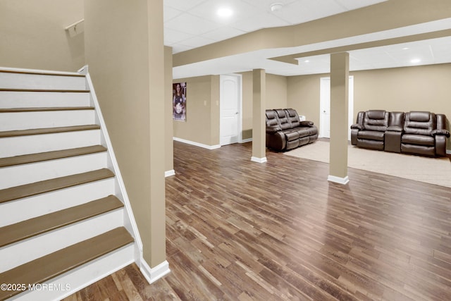 finished below grade area featuring stairway, baseboards, and wood finished floors