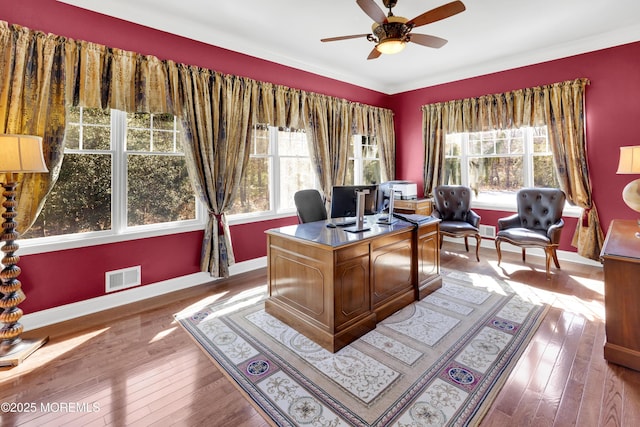 office area with a wealth of natural light, hardwood / wood-style flooring, visible vents, and baseboards