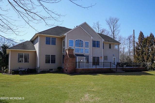 back of property featuring roof with shingles and a yard