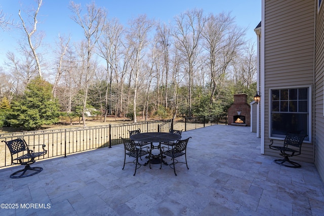 view of patio / terrace featuring a warm lit fireplace and outdoor dining space