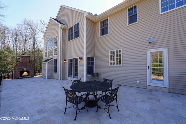 rear view of house with a patio and an outdoor brick fireplace