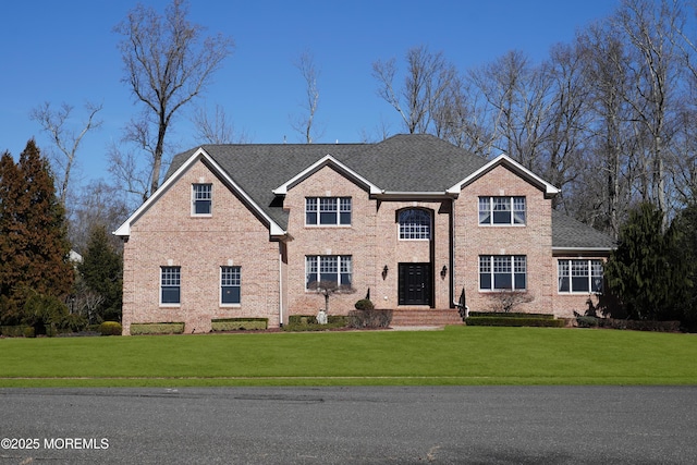 traditional-style house with brick siding, roof with shingles, and a front yard