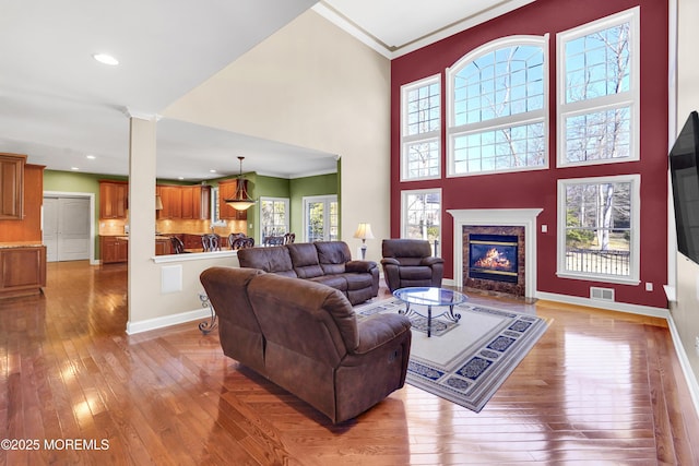 living room with visible vents, plenty of natural light, a premium fireplace, and hardwood / wood-style flooring