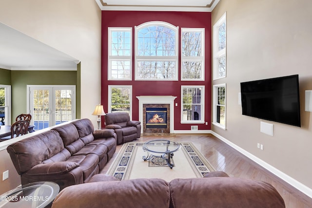 living room featuring a high end fireplace, wood finished floors, crown molding, and french doors