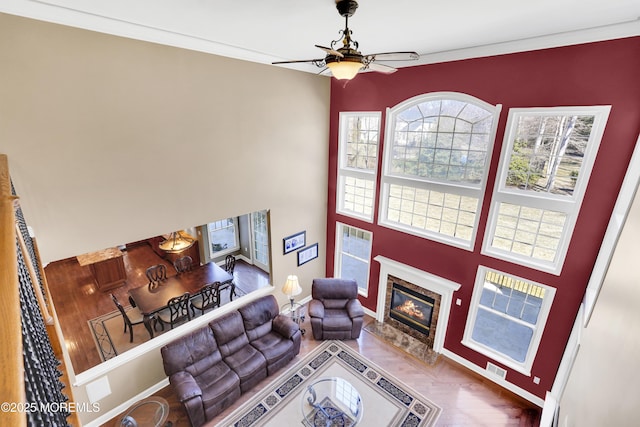 living area featuring baseboards, a ceiling fan, and a high end fireplace