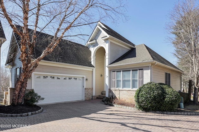 view of front of house with a garage, brick siding, decorative driveway, and a shingled roof