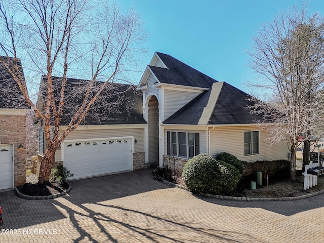 view of front of home featuring a garage, decorative driveway, and a shingled roof