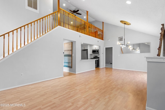 unfurnished living room with wood finished floors, visible vents, baseboards, and ceiling fan with notable chandelier