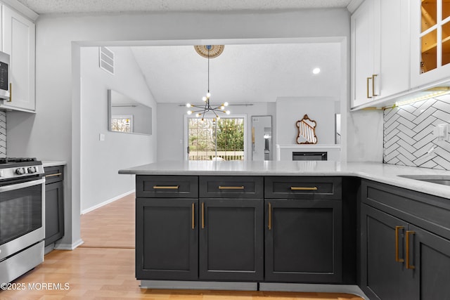 kitchen featuring light wood-style flooring, a peninsula, stainless steel appliances, light countertops, and white cabinetry