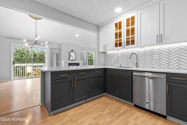 kitchen with light wood finished floors, a peninsula, light countertops, white cabinetry, and stainless steel dishwasher