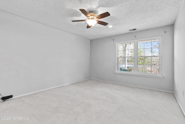 carpeted empty room with baseboards, visible vents, ceiling fan, and a textured ceiling