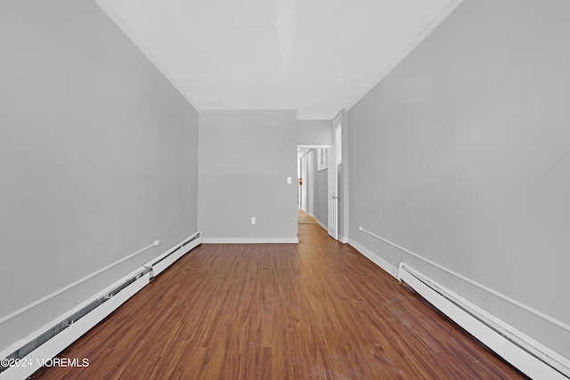 unfurnished living room with baseboards, a baseboard heating unit, baseboard heating, and wood finished floors