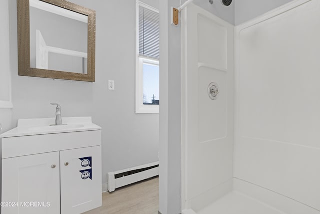 full bathroom with a baseboard heating unit, wood finished floors, vanity, and walk in shower