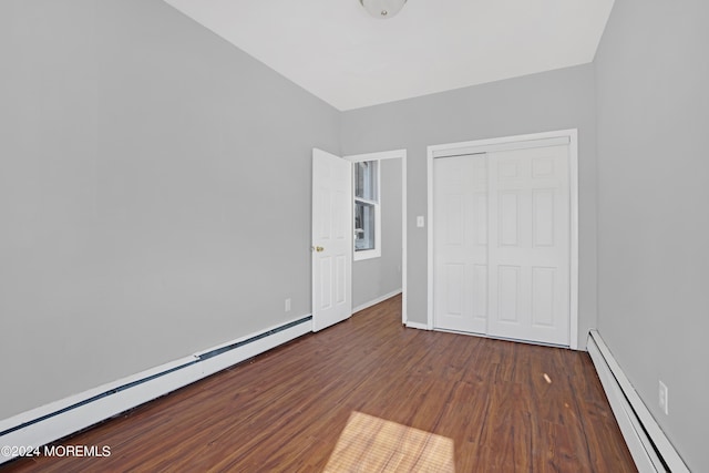 unfurnished bedroom with a closet, baseboards, baseboard heating, and wood finished floors