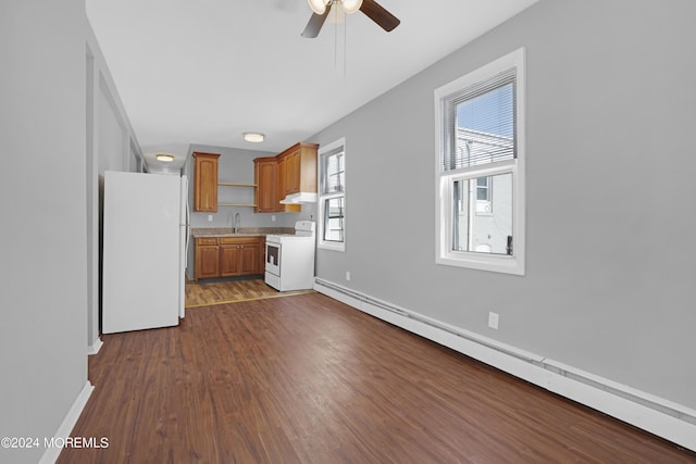 kitchen with a baseboard radiator, under cabinet range hood, white appliances, dark wood-type flooring, and light countertops