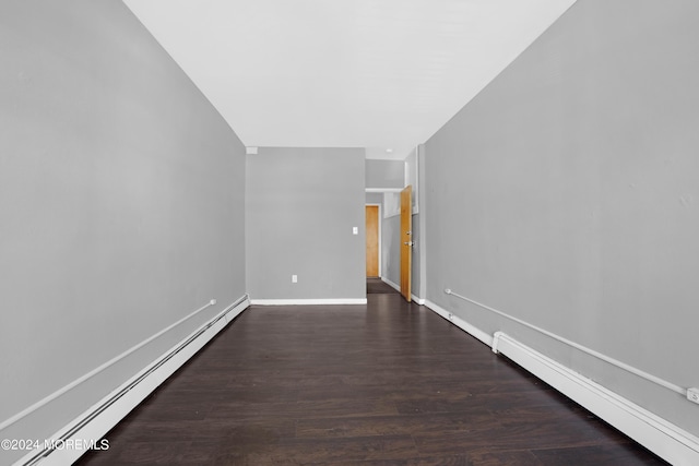 spare room with a baseboard heating unit, dark wood-style flooring, and baseboards