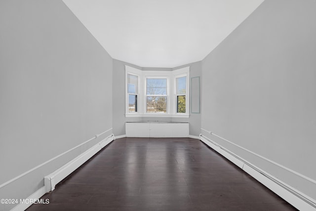 unfurnished room with baseboards, baseboard heating, and dark wood-type flooring