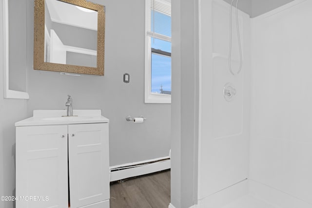 full bathroom featuring a baseboard radiator, a shower, wood finished floors, and vanity