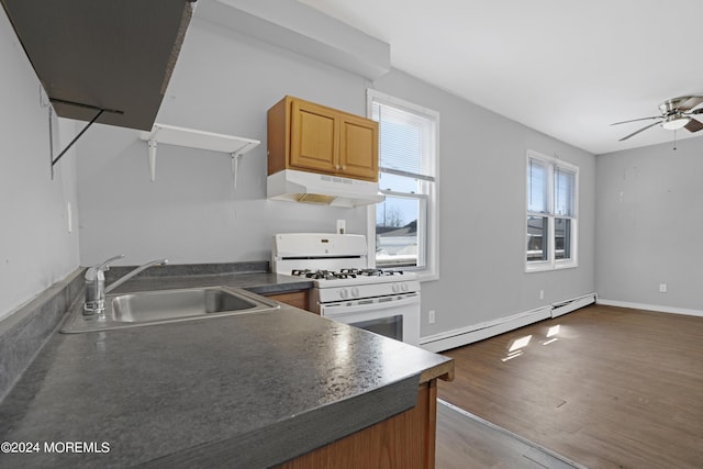 kitchen with white gas stove, under cabinet range hood, a sink, light wood-style floors, and baseboard heating