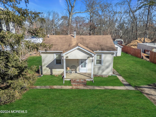 view of front of property featuring a shingled roof, fence, and a front yard