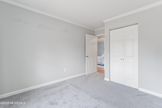 unfurnished bedroom with carpet, a closet, ornamental molding, and baseboards