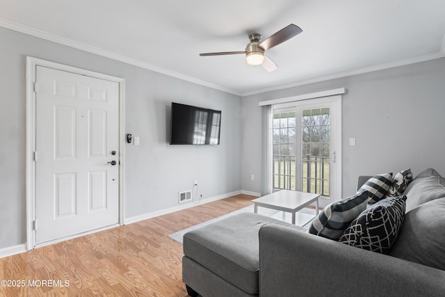 living area with crown molding, light wood-style flooring, baseboards, and ceiling fan