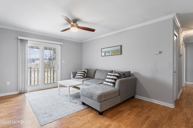 living area featuring baseboards, ceiling fan, wood finished floors, and crown molding