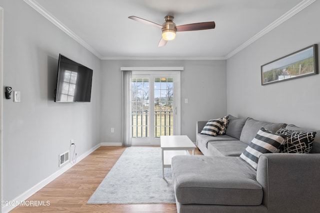 living area featuring light wood-style floors, visible vents, crown molding, and baseboards