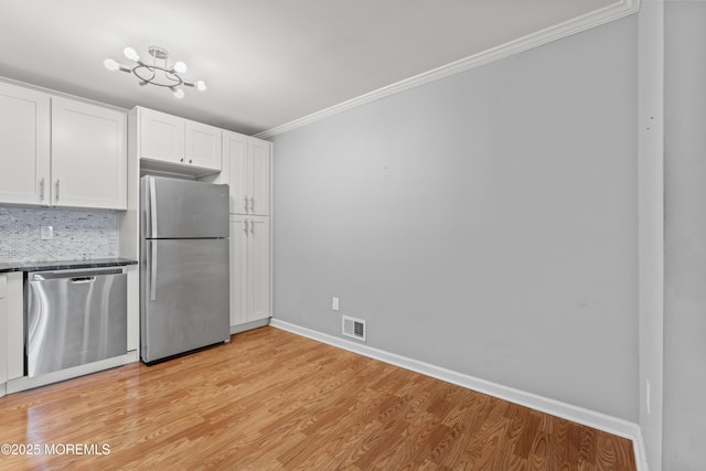 kitchen with visible vents, white cabinets, stainless steel appliances, crown molding, and backsplash