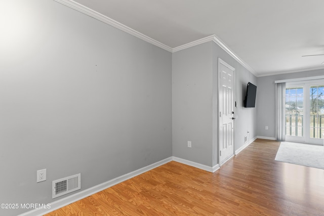 unfurnished room with light wood finished floors, baseboards, visible vents, and ornamental molding