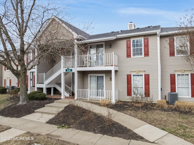 multi unit property with a balcony, a chimney, a porch, and cooling unit