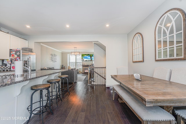 dining space with ornamental molding, dark wood-style flooring, recessed lighting, and a notable chandelier